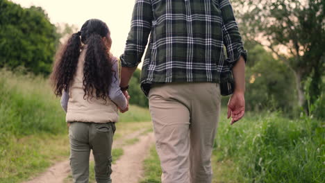 father and daughter walking hand in hand in nature