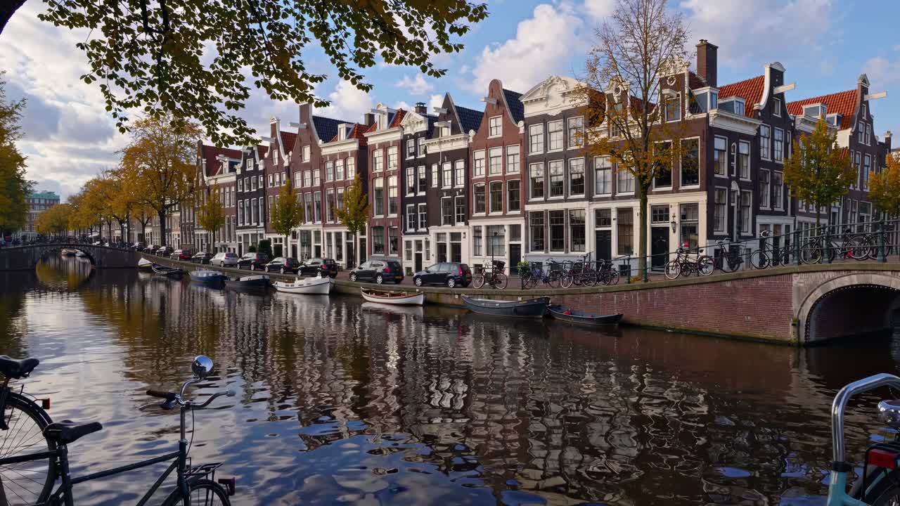 Video captures a scenic canal in Amsterdam from a low angle, showcasing historic buildings, boats