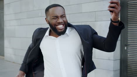 african businessman reading good news on phone. employee celebrating victory