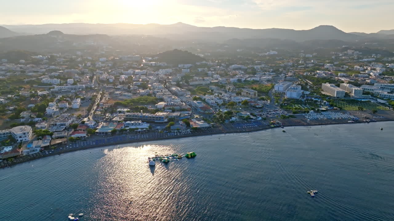 Drone rotating in front of the beach and town, golden hour in Faliraki, Rhodes