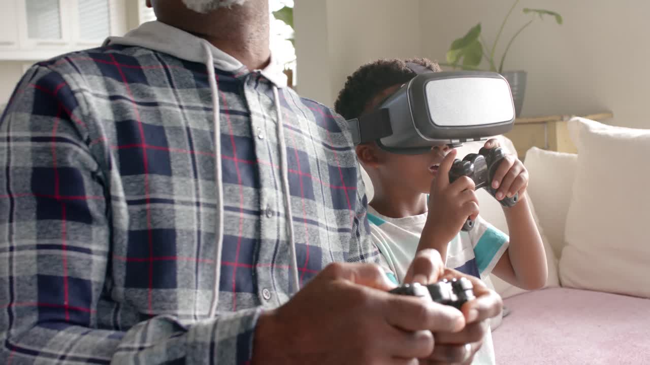 Nonno e nipote afroamericani che si divertono usando un visore VR, al rallentatore
