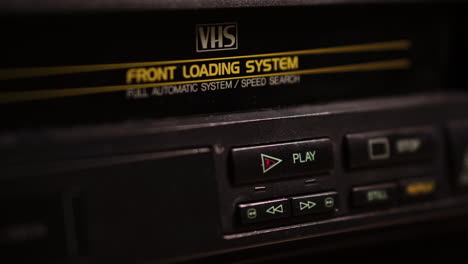 loading vhs video cassette tape and pressing play button on vcr, close up