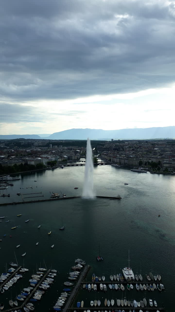 Vertical, aerial: water fountain of Geneva during the day (Rade of Geneva) in canton of Geneva, Switzerland, pull out drone shot