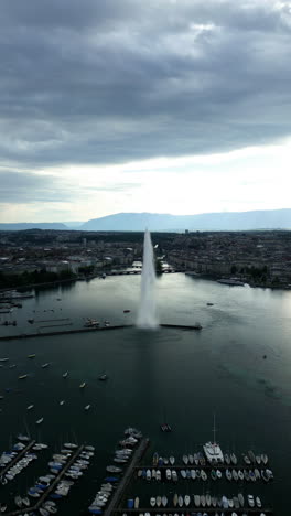 vertical, aerial: water fountain of geneva during the day (rade of geneva) in canton of geneva, switzerland, pull out drone shot