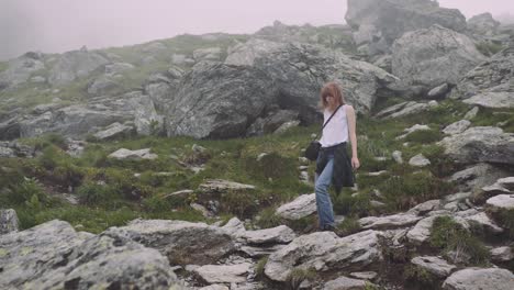 a young woman hiker climbs mountains with photo camera. transfagarasan, carpathian mountains in romania