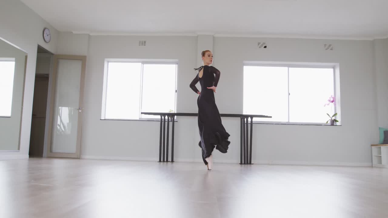Caucasian female ballet dancer practicing ballet during a dance class in a bright studio