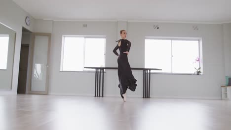 caucasian female ballet dancer practicing ballet during a dance class in a bright studio