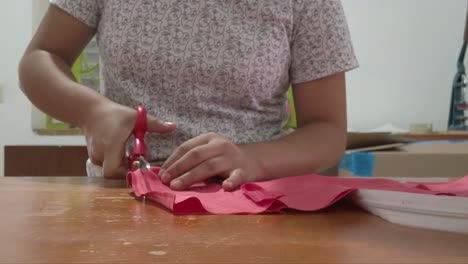 dolly in shot of a latin seamstress cutting a piece of fabric with scissors