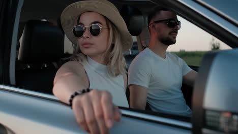 happy young couple sitting inside their car and enjoying road trip, focus on the girl, travel and adventure concept