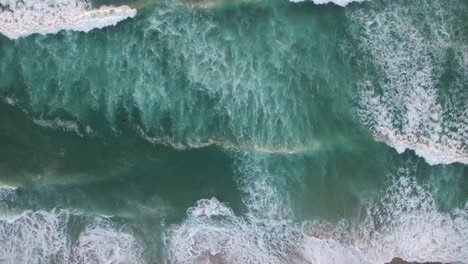 An-vista-aérea-perspective-looking-straight-down-at-the-ocean-with-waves-rolling-in