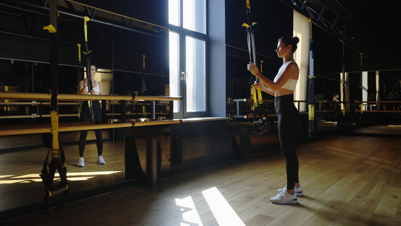 Woman exercising with suspension trainer in a modern gym