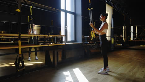 woman exercising with suspension trainer in a modern gym