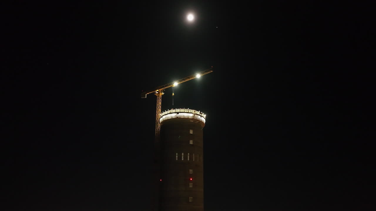 Low angle drone shot orbiting the Prysmian tower construction, night in Finland