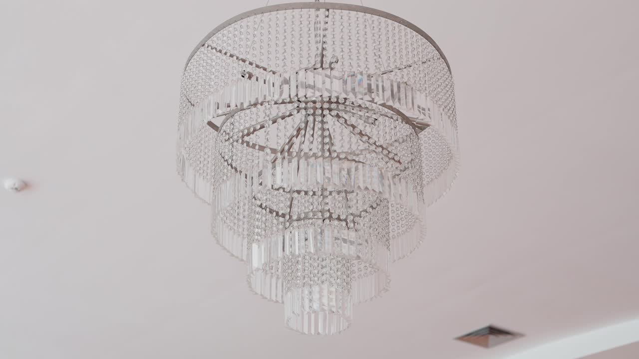 elegant multi tiered crystal chandelier hangs from white ceiling in a modern indoor space