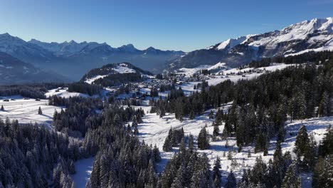 aerial approaching flight showing amden village surrounded by snowy mountains in switzerland