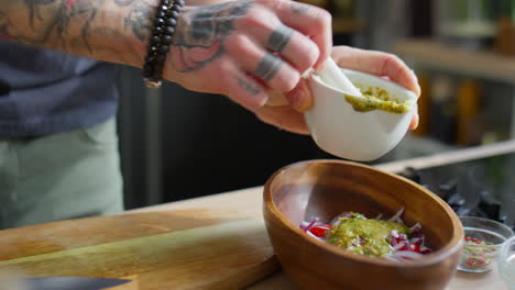 adding pesto dressing to salad