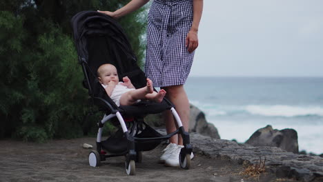 amidst the ocean's beauty, a young mother of this sweet family shares moments with her baby in the stroller, portraying her deep affection and nurturing nature