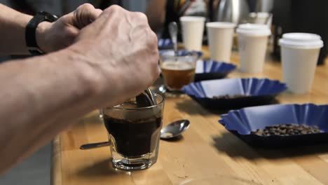 scraping top layer during coffee cupping using two spoons, slow motion close up