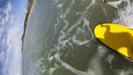 Vertical-Shot---Surfer-On-A-Surfboard-Riding-Waves-In-The-Ocean-On-A-Sunny-Summer-Day