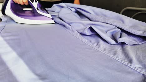 man ironing blue striped shirt - slow motion video