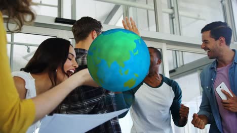 animation of rotating globe over happy diverse colleagues celebrating at casual office meeting