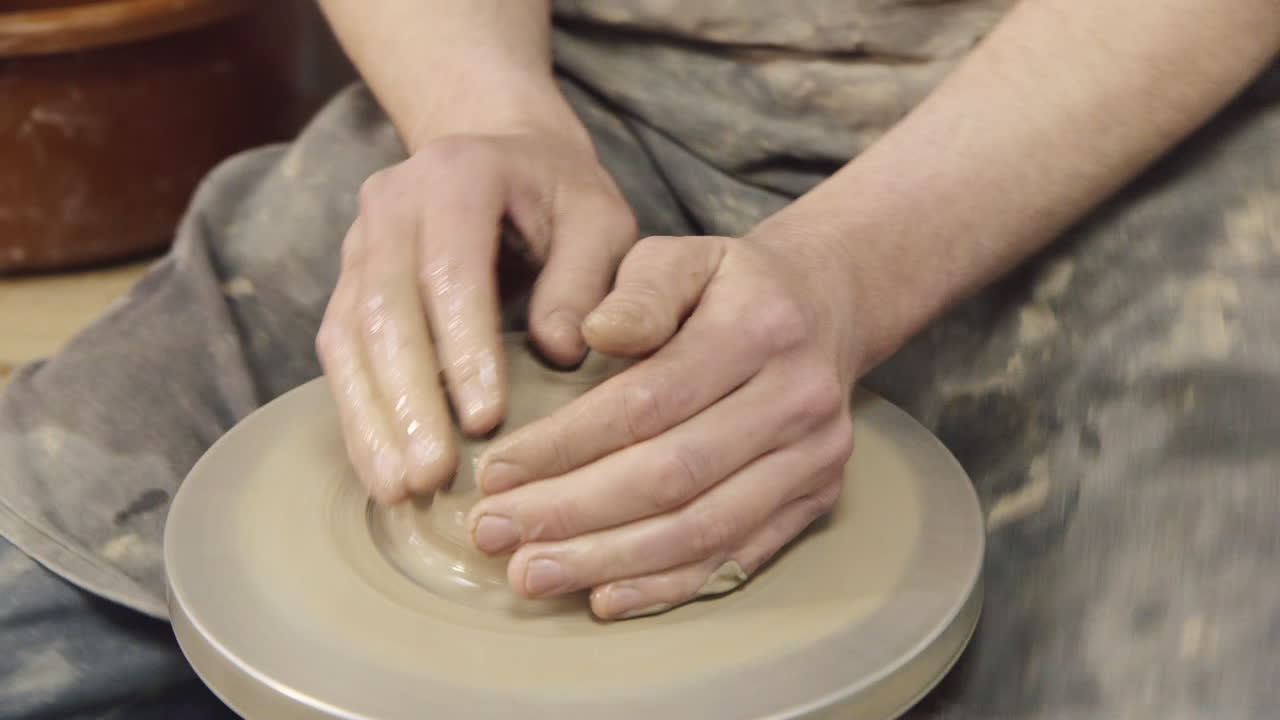 las manos de un alfarero hacen una jarra en un torno de alfarero