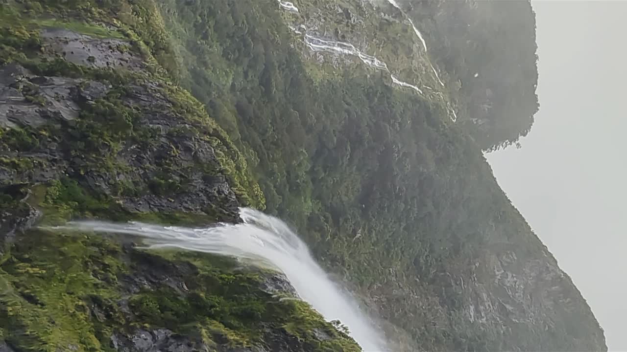 una masa de agua fluye por un acantilado escarpado durante una fuerte tormenta en miford sound, nueva zelanda.