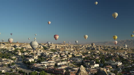 Cappadocia,-Turkey,-Panorama-of-Goreme-With-Hot-Air-Balloons-Flying-Above-Town-and-Landscape-on-Sunny-Morning