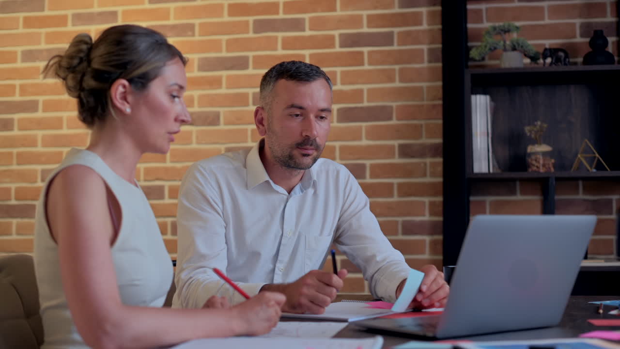 Un uomo e una donna parlano e indicano un computer su una scrivania in un ufficio