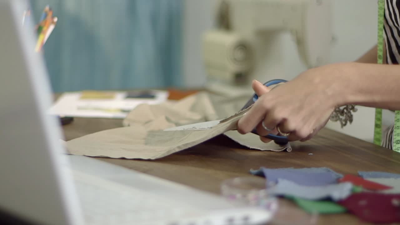 Primer plano de unas manos cortando tela con tijeras para un proyecto de costura
