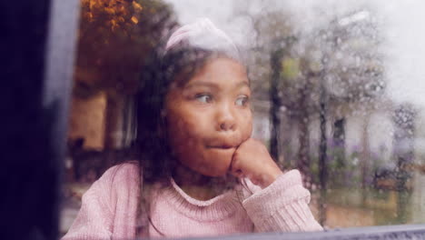 bored female child looking outside on a wet winter