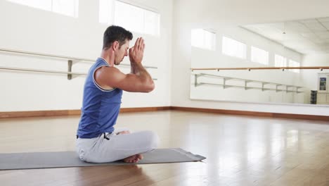 Hombre-Caucásico-Enfocado-Practicando-Meditación-De-Yoga-En-El-Gimnasio,-Cámara-Lenta