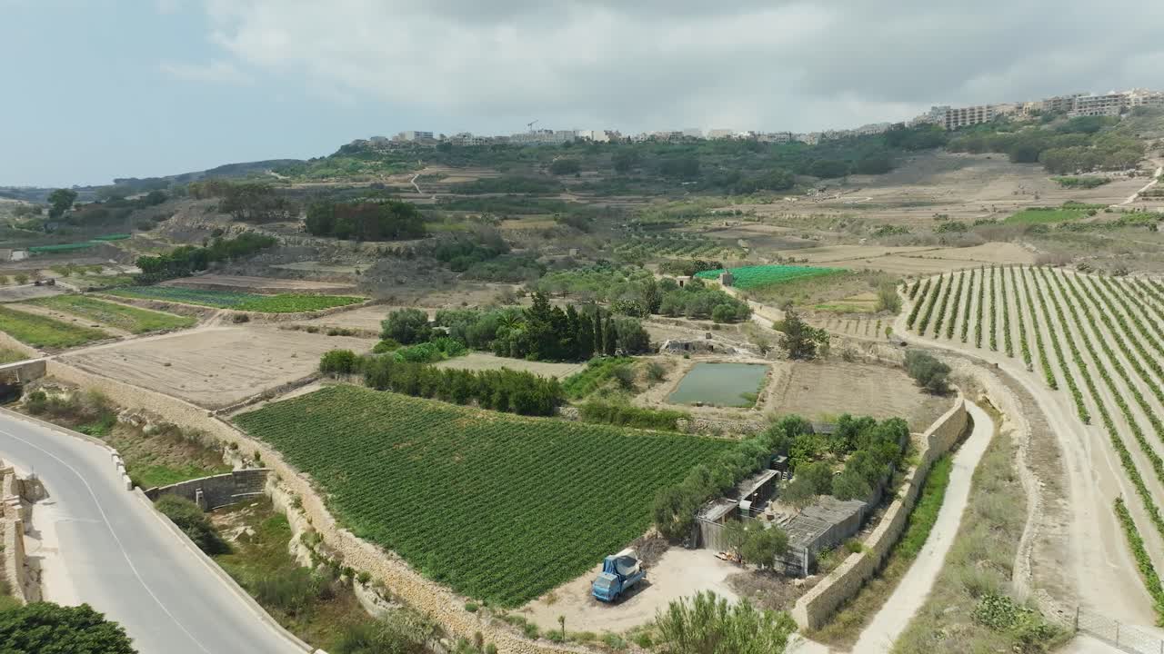 드론 영상은 농경지를 가로질러 는 시골 도로의 높은 고도 전망을 제공하며, 토지 사용의 다양성과 자연의 아름다움을 포착합니다.