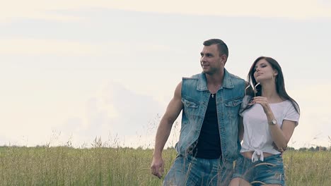 young couple in summer dressing hugs and walks on field