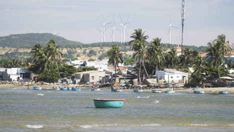 toma estática de la escena de la playa con un barco coracle amarrado, turbinas eólicas en el fondo