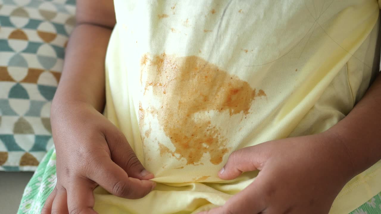 niño pequeño con mancha de comida en la camisa