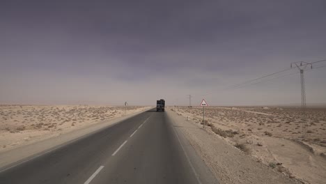Driving behind a truck in the arid desert landscape of Tunisia during the heat of the day