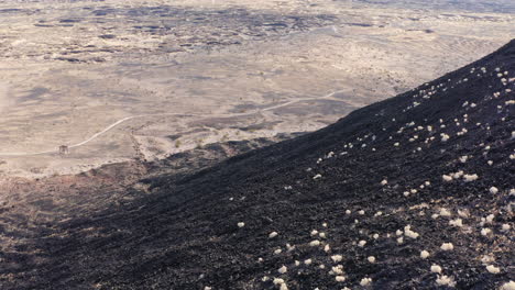 aerial view flying down the side of the volcanic amboy crater looking out at the textured alien landscape