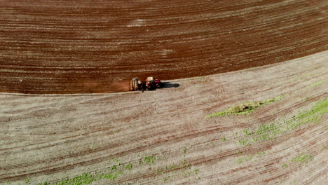 Toma-De-Vista-Aérea-De-Un-Agricultor-En-La-Siembra-De-Tractores,-Sembrando-Cultivos-Agrícolas-En-El-Campo