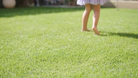 a little girl in a dress is blowing soap bubbles in the backyard on a sunny summer day