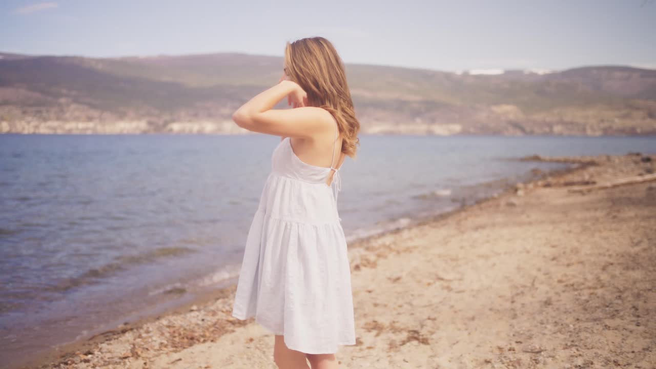 Girl modeling a white dress on a windy beach