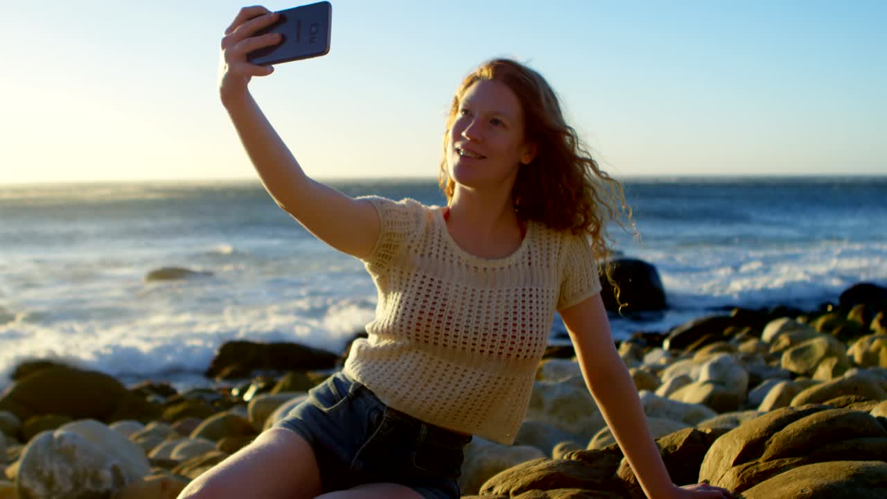 mujer tomando una selfie con teléfono móvil en la playa 4k