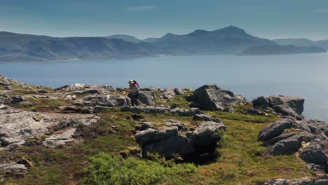 a woman hiker is walking on the top of a mountain in kvaloya