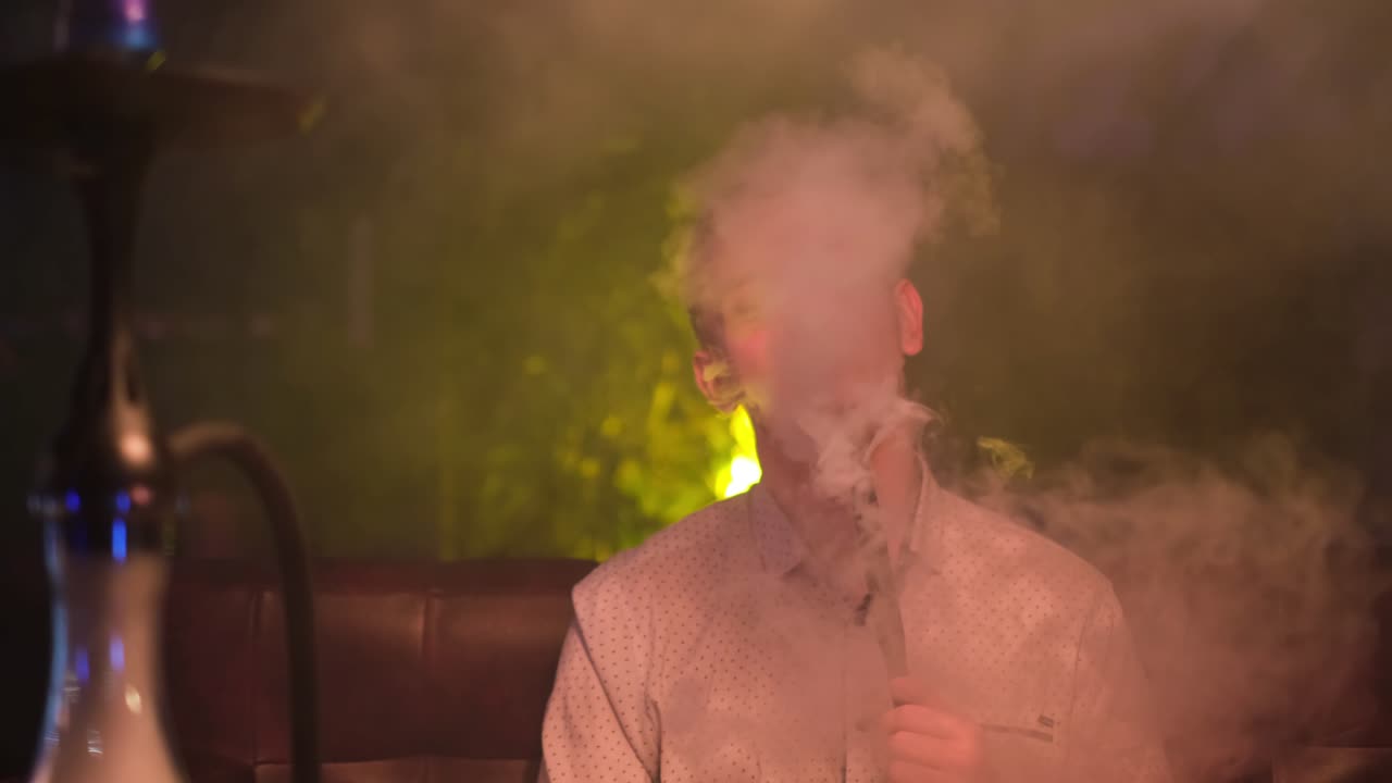 hombre fumando narguile en un club nocturno