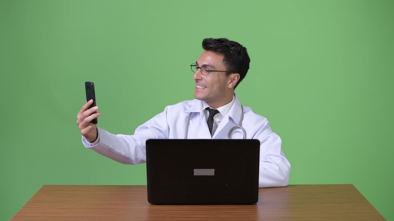 Giovane e affascinante medico ispanico su sfondo verde.