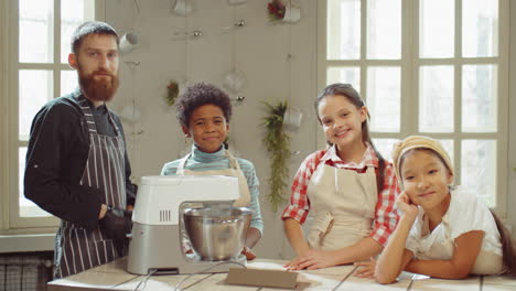 retrato del chef y los niños alegres en la clase de cocina