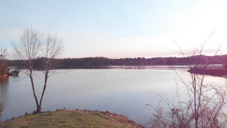 drone footage flying through a covered swing set then out over a point of land and then out over the lake at sunset