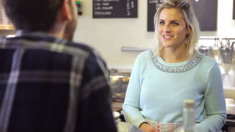 woman serving male customer in coffee shop