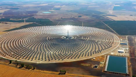 solar panels in a large thermal circular power plant with the reflection of the sunlight in the panels. renewable and pollution-free energy in a solar farm in spain- aerial view with a drone - environmental concept