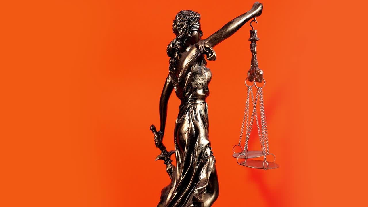 Statua dorata della Giustizia con bilancia e spada che ruota